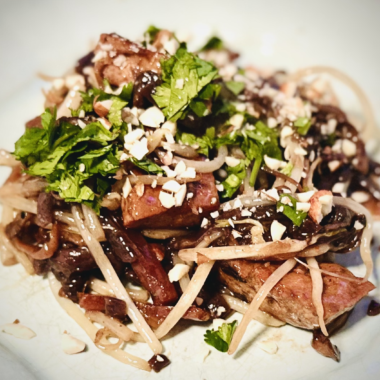 Plate of vegan pad thai with glossy rice noodles, bean sprouts, fresh cilantro, and crushed peanuts