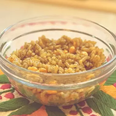 Bowl of finished arroz verde Mexican green rice with corn on a colorful floral placemat