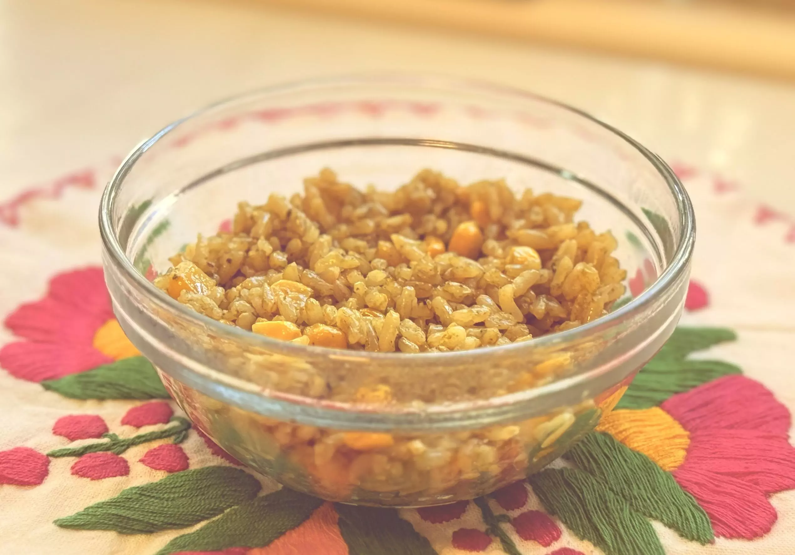Bowl of finished arroz verde Mexican green rice with corn on a colorful floral placemat