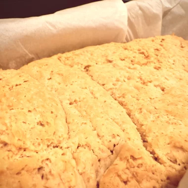 Golden vegan gluten-free brioche bread fresh from the oven in a parchment-lined loaf pan