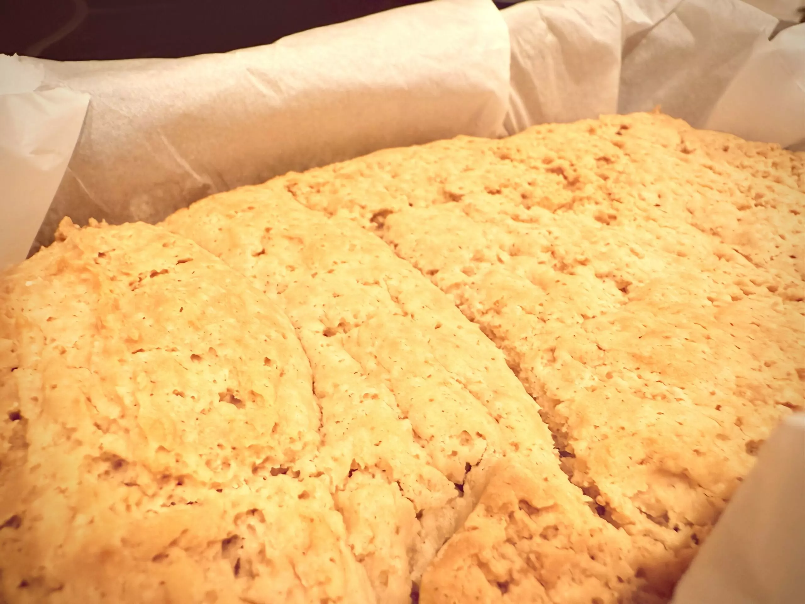 Golden vegan gluten-free brioche bread fresh from the oven in a parchment-lined loaf pan