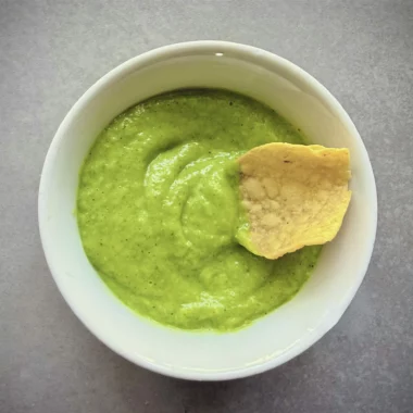 avocado-tomatillo salsa in a bowl with a chip in it