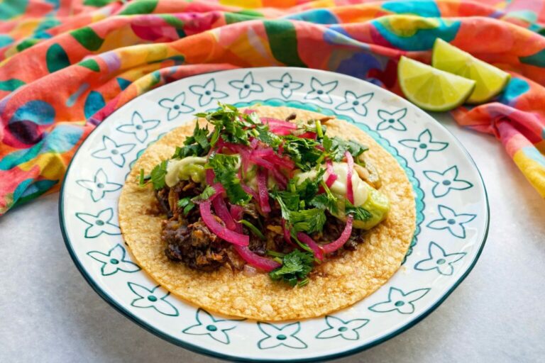assembled vegan oyster mushroom taco with beans, oyster mushrooms, onion, cilantro, salsa and cashew crema