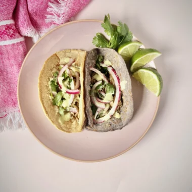 two oyster mushroom tacos with fixings and lime to the side